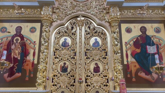 Close-up of the intricate golden Royal Doors (Holy Doors) of the iconostasis inside the Assumption Cathedral, Astrakhan Kremlin. Featuring ornate woodcarvings and traditional Orthodox