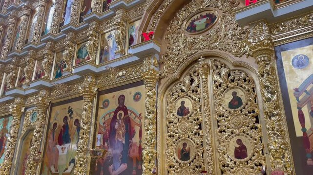 Close-up of the golden iconostasis and Royal Doors inside the Assumption Cathedral, Astrakhan Kremlin, Russia. Featuring intricate carvings and traditional Orthodox religious icons