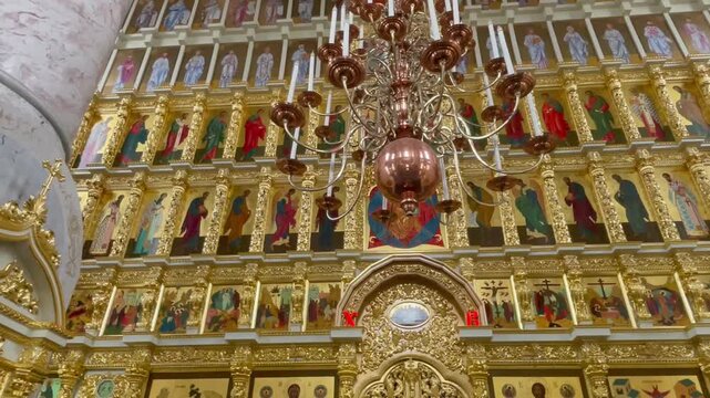 Ornate golden iconostasis and copper chandelier inside the Assumption Cathedral of the Astrakhan Kremlin, Russia. A masterpiece of Orthodox religious architecture and sacred heritage