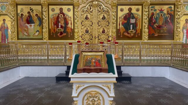 Interior view of the Assumption Cathedral in the Astrakhan Kremlin, Russia, featuring the ornate golden iconostasis, sacred religious icons, and a central lectern