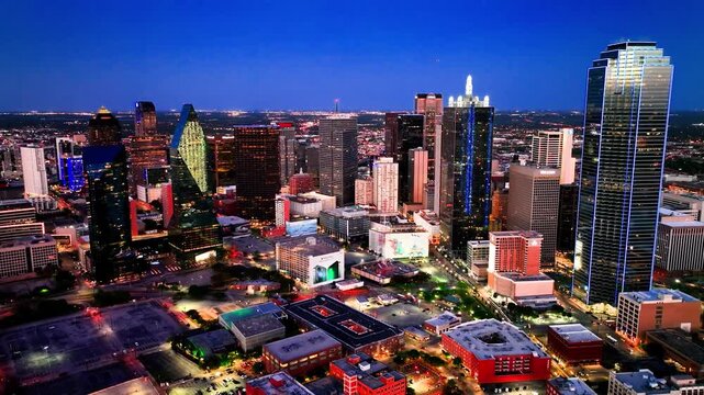 Cinematic blue hour aerial view of the illuminated Dallas skyline and downtown business district.