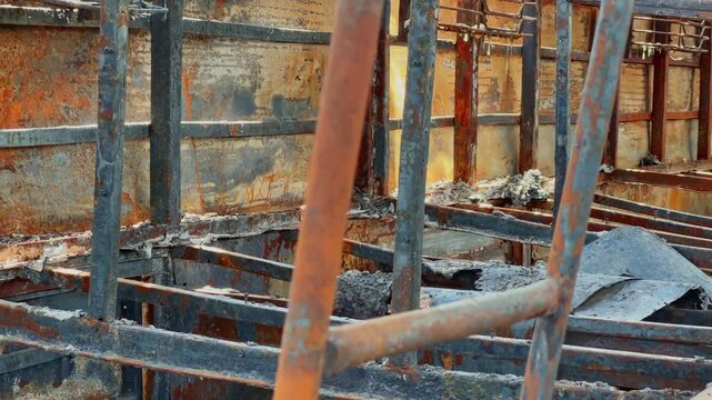 Closeup of charred sleeper bus berth frames with exposed metal structure, ash residue and severe fire destruction inside damaged passenger vehicle!
