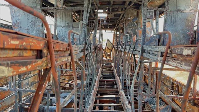 Interior view of burned sleeper bus showing charred metal berth frames, destroyed passenger compartments and severe fire damage under daylight conditions!