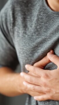 A Close-Up of a Man Experiencing Discomfort, With a Focus on His Hands Clutching His Chest, Capturing an Intense Moment of Physical Distress and Concern.
