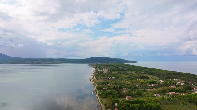 Drone view of Riserva Naturale Statale Isola di Varano with forests, calm lake water and dark storm clouds.