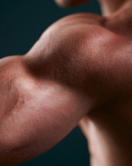Fototapeta premium Strong arm muscles flex under soft lighting. Toned skin glistens with subtle shine. Background fades into deep, dark tone. Focus on power and physical strength. Ideal for fitness, health
