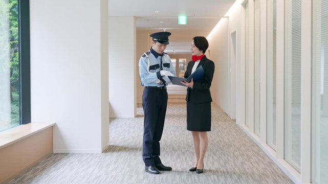 ロビーで会話する男性警備員と女性スタッフ
