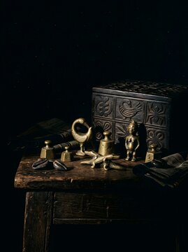 Akan Brass Gold Weights and Carved Adinkra Wooden Box Dark Still Life on Rustic Table"