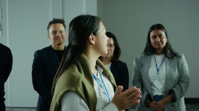 Diverse young business professionals connect and collaborate at a corporate conference event. A confident woman speaks, sharing ideas with her engaged team, fostering professional growth.