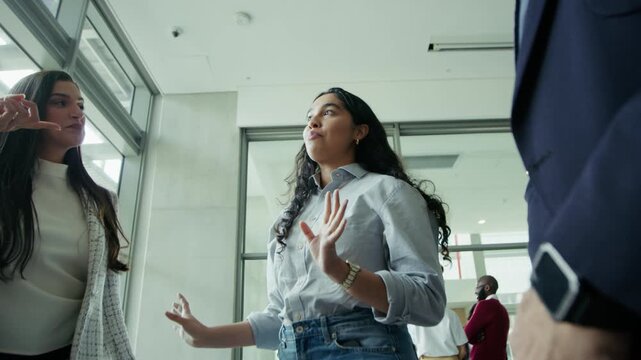 Young professional engaging in lively discussion with colleagues, expressing ideas and collaborating in a corporate office environment. Demonstrating effective communication and teamwork.