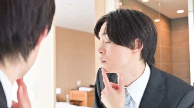 朝のホテルの鏡で身だしなみを確認するビジネスマン就活や出張などの営業前チェックイメージ　第一印象大事だね動画