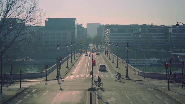 Cars and cyclists cross parisian bridge over river seine during morning rush hour.