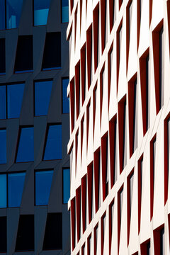 Red facade with windows creating strong contrast against a dark building exterior, where urban architecture pattern meets sharp shadow