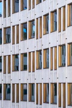 Concrete facade with windows and vertical pattern across a building exterior, where urban architecture detail appears in warm reflected light