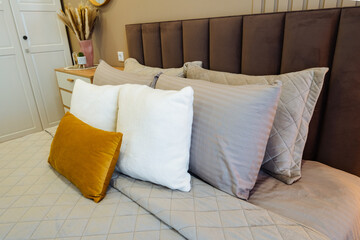 Obraz premium Luxurious and cozy bedding complemented by tasteful decorative accents. Refined bedroom design featuring soft furnishings and sophisticated decorative elements for relaxation