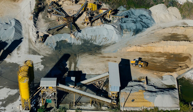 Industrial quarry machinery depositing aggregate piles in aerial site