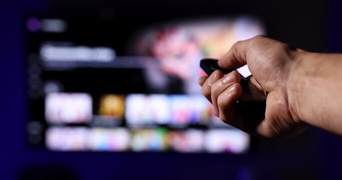 remote control in hand choosing TV content to watch. smart interactive television, content on demand concept