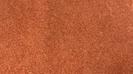 Fototapeta premium Close-up of reddish textured fibrous material with dense, uniform pattern and fine strands creating a rough surface appearance