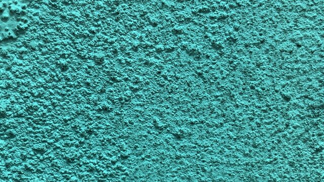 Close-up of coarse greenish textured wall emphasizing granular surface and consistent rough coating pattern