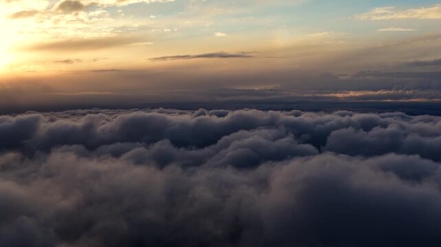 Aerial view of a dense sea of clouds at sunset with the golden sun glowing over the horizon above the White Mountains in Mono County, California, United States.
