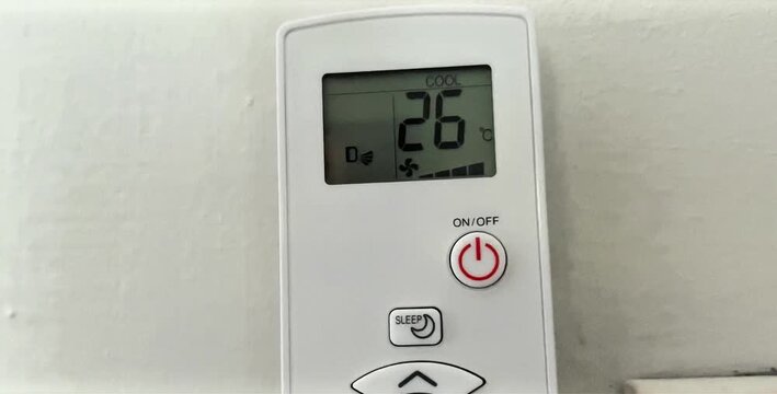 Close-up of an air conditioner remote control displaying the current temperature setting