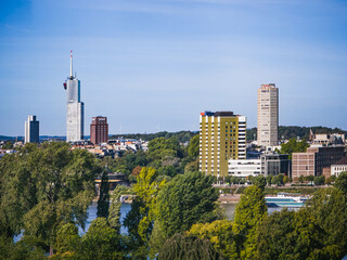 Fototapeta premium Cologne, Germany - September 7, 2025: Scenic view of modern Cologne skyline with Colonius Tower, urban architecture, green trees and Rhine River on a sunny day in Germany.