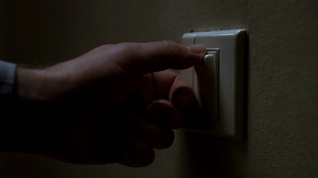Hand reaches for light switch in dark room. Action captures moment of turning off light in private setting with shadowy walls. Concept of home, energy saving, interior design