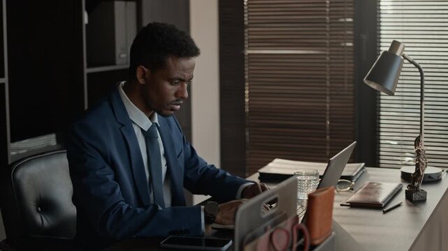 Serious lawyer sitting at desk, using laptop while preparing for divorce consultation in office