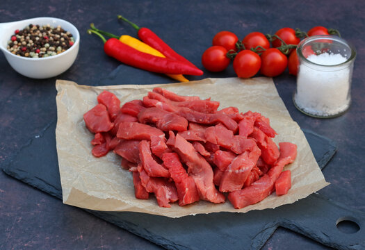 Fresh sliced ​​beef on a slate plate with chili, tomatoes, and sea salt.