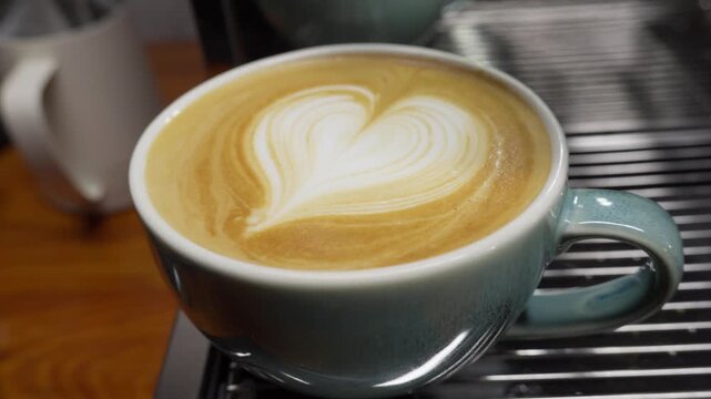 Closeup view of a fresh latte with heart-shaped art on milk foam in a coffee shop