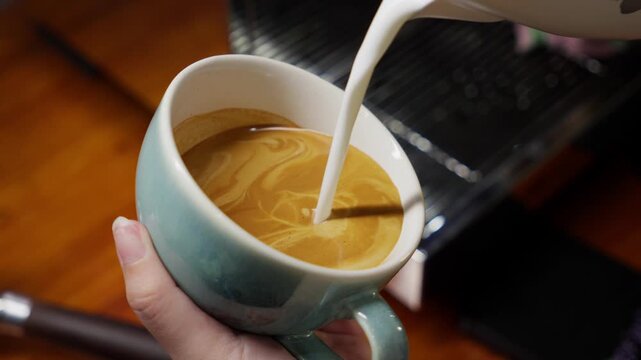 Barista hand making Latte Art in a cup of coffee. Close up