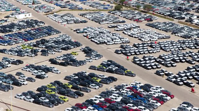 Vast parking lot filled with thousands of new cars neatly organized in rows, showcasing the scale of automobile manufacturing, import, export, and distribution for the global market