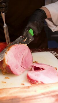 Chef in Black Gloves Slicing Roasted Ham with Carving Knife