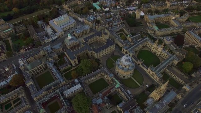 4K aerial view of Oxford with iconic Radcliffe Camera dome, Bodleian Library, Sheldonian Theatre, All Souls College and University Church spire in autumn evening light.