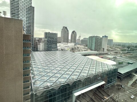 den haag, netherlands - august 28 2025: A vast urban environment showcases contemporary buildings under an overcast sky with unique roof design and city life below.