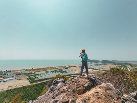 Person standing on rugged cliff observing distant island landscape