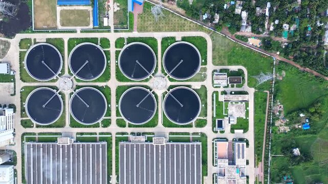Aerial view of a sewage treatment plant with circular clarifier tanks and industrial buildings surrounded by greenery in Dhaka, Dhaka Division, Bangladesh.
