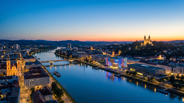 Panoramic aerial view of Linz, Austria at dusk with the Danube River and historic architecture.