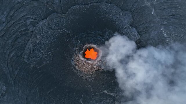 Aerial view of the Erta Ale volcano crater with glowing orange lava and rising white smoke in the Danakil Desert Dalol, Afar, Ethiopia.