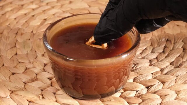 Vertical 4K Close Up Hand Dipping Pretzel into Salted Caramel