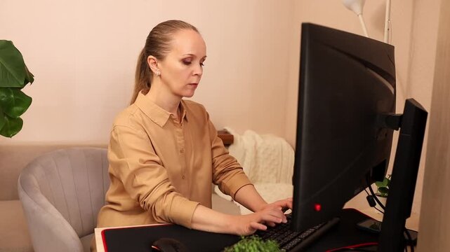A focused young Caucasian woman working on a computer at her desk.