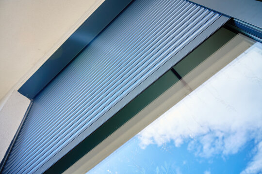 Exterior roller shutter partially open on modern window