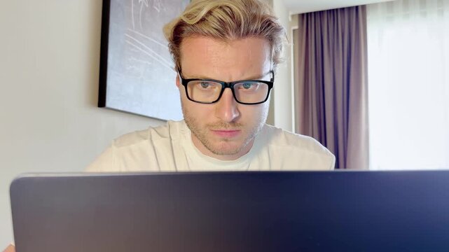 A young man works on a laptop from home