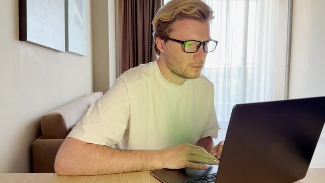 A young man works on a laptop from home