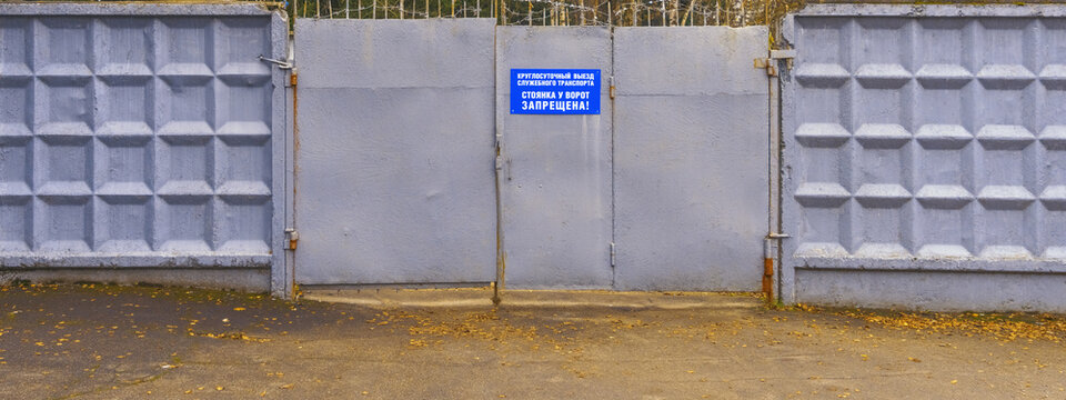 Residential compound features sturdy concrete fence with warning label and visible metal fastenings