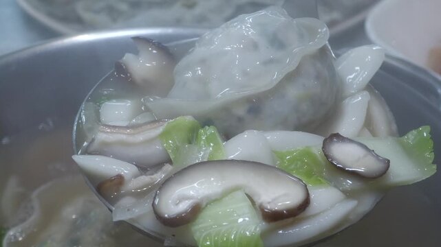 Ladle ladle full of steaming hot rice cake and dumpling soup