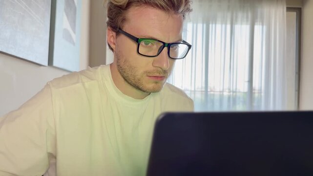 A young man works on a laptop from home