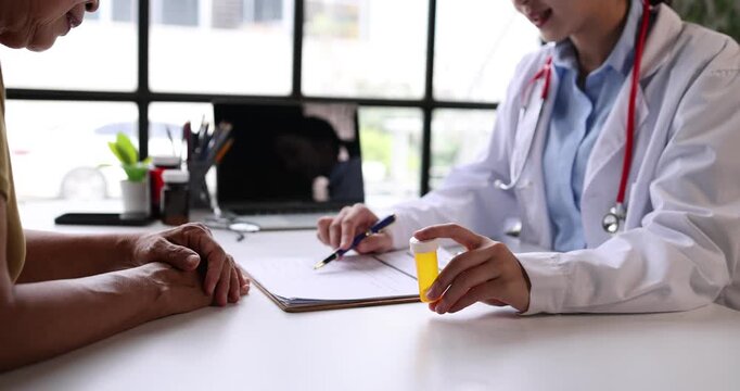 Female doctor holding a bottle of pills explaining a prescription and dosage to an elderly patient during a clinic consultation, offering guidance and care for treatment and recovery