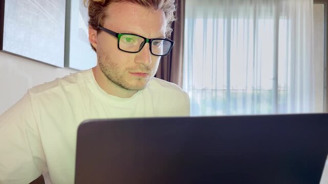 A young man works on a laptop from home