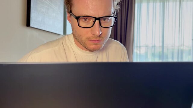 A young man works on a laptop from home